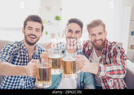 Bachelor`s Männerleben. Prost! Nahaufnahme von drei glücklichen, schönen Männern, die den Sieg feiern und ein klirrrendes Bier trinken. Sie sind Fans des Sports Stockfoto